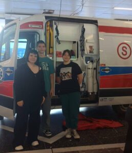 Na zdjęciu członkowie zespołu ratownictwa medycznego na tle karetki pogotowia ratunkowego.