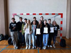 Grupowe zdjęcie reprezentacji dziewcząt i chłopców wraz z opiekunami po zawodach pływackich.