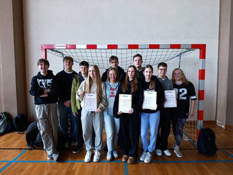 Grupowe zdjęcie reprezentacji dziewcząt i chłopców wraz z opiekunami po zawodach pływackich.